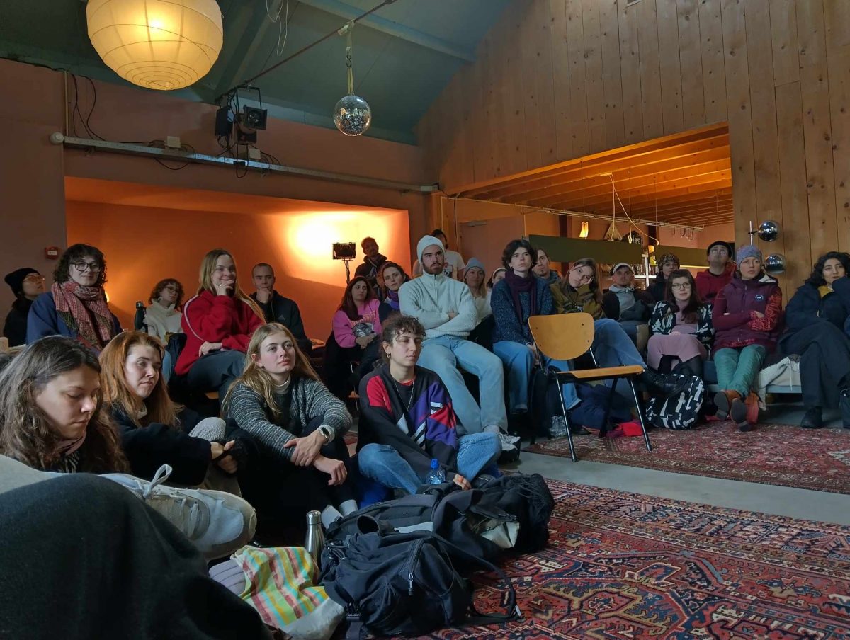 Group of tudents sitting on a floow where is two big oriental carpets. 